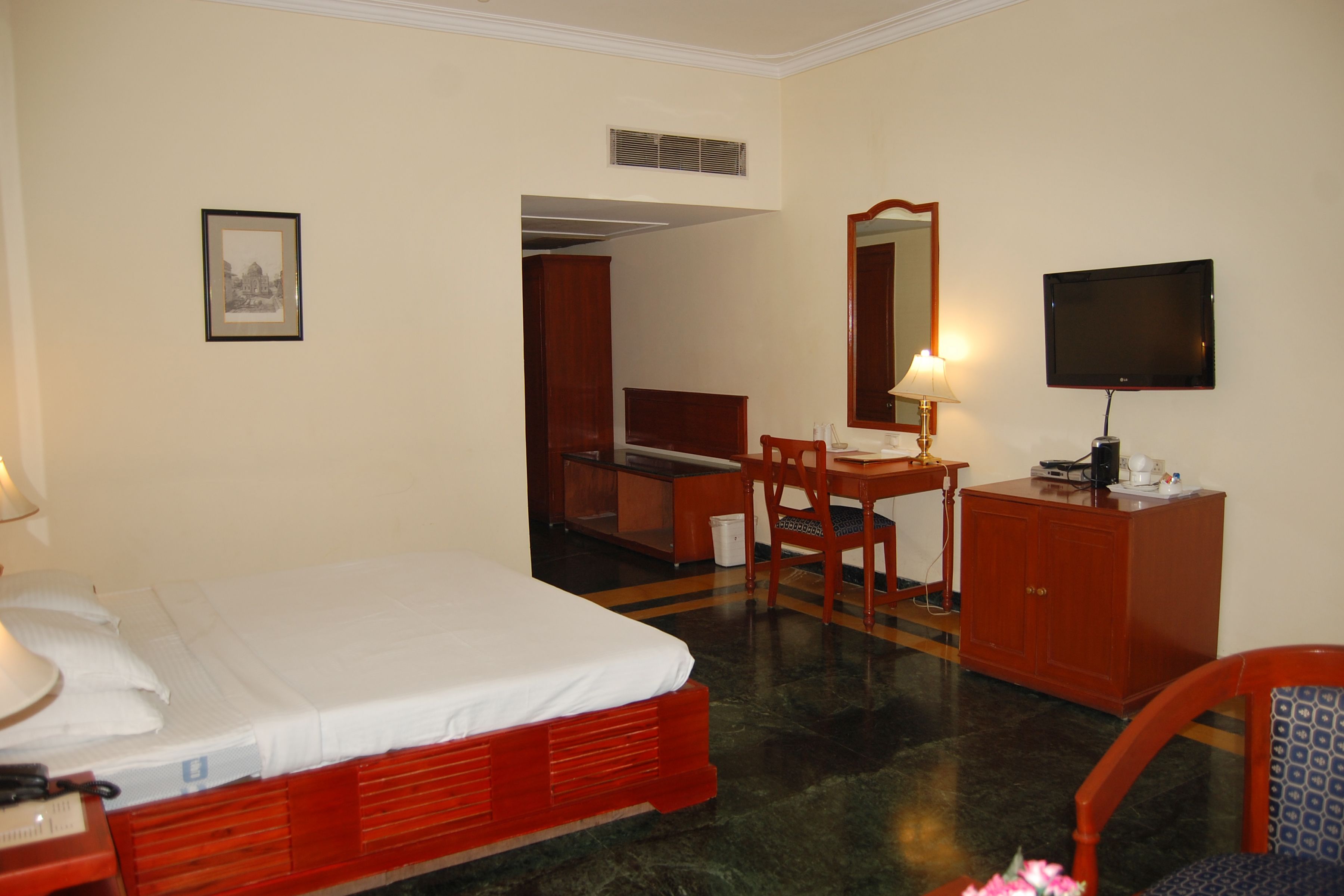 A hotel room with a bed, a desk, a chair, a television, and a cabinet.