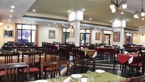 Un amplio comedor con múltiples mesas y sillas, dispuesto en estilo banquete.