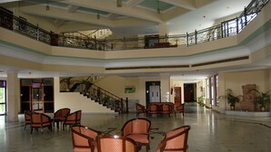A spacious lobby with a high ceiling, a staircase, and multiple seating areas. - The Royal Residency (Gaya)