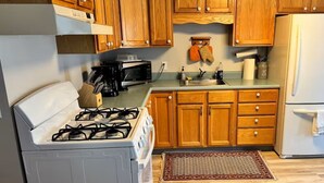 Una cocina con gabinetes de madera, estufa a gas, microondas y refrigerador.