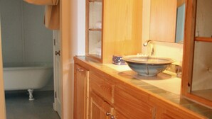 A bathroom with wooden cabinets, a sink, and a mirror. - Cozy Living Close to the Beach (Bay St Louis)