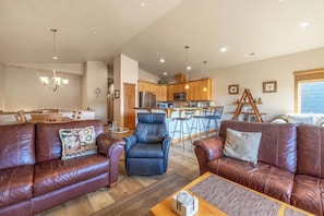 A spacious living room with leather sofas, a blue armchair, and a wooden coffee table.