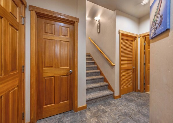 A wooden door, a staircase with a handrail, and a painting on the wall.