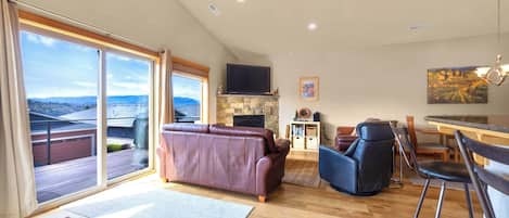 Un salón espacioso con un ventanal grande, chimenea, televisor y comedor.