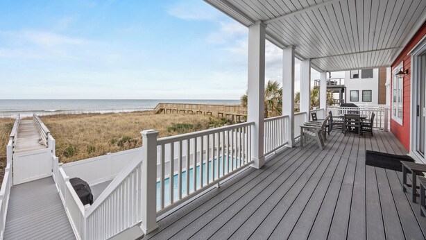 A wooden deck with a pool, white railings, and a view of the beach. - 🌊Less Stress: Oceanfront Home with Private Pool + Elevator🌊 (Kure Beach)