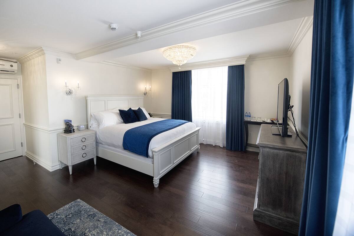 A bedroom with a large bed, a dresser, a desk, and a chandelier.