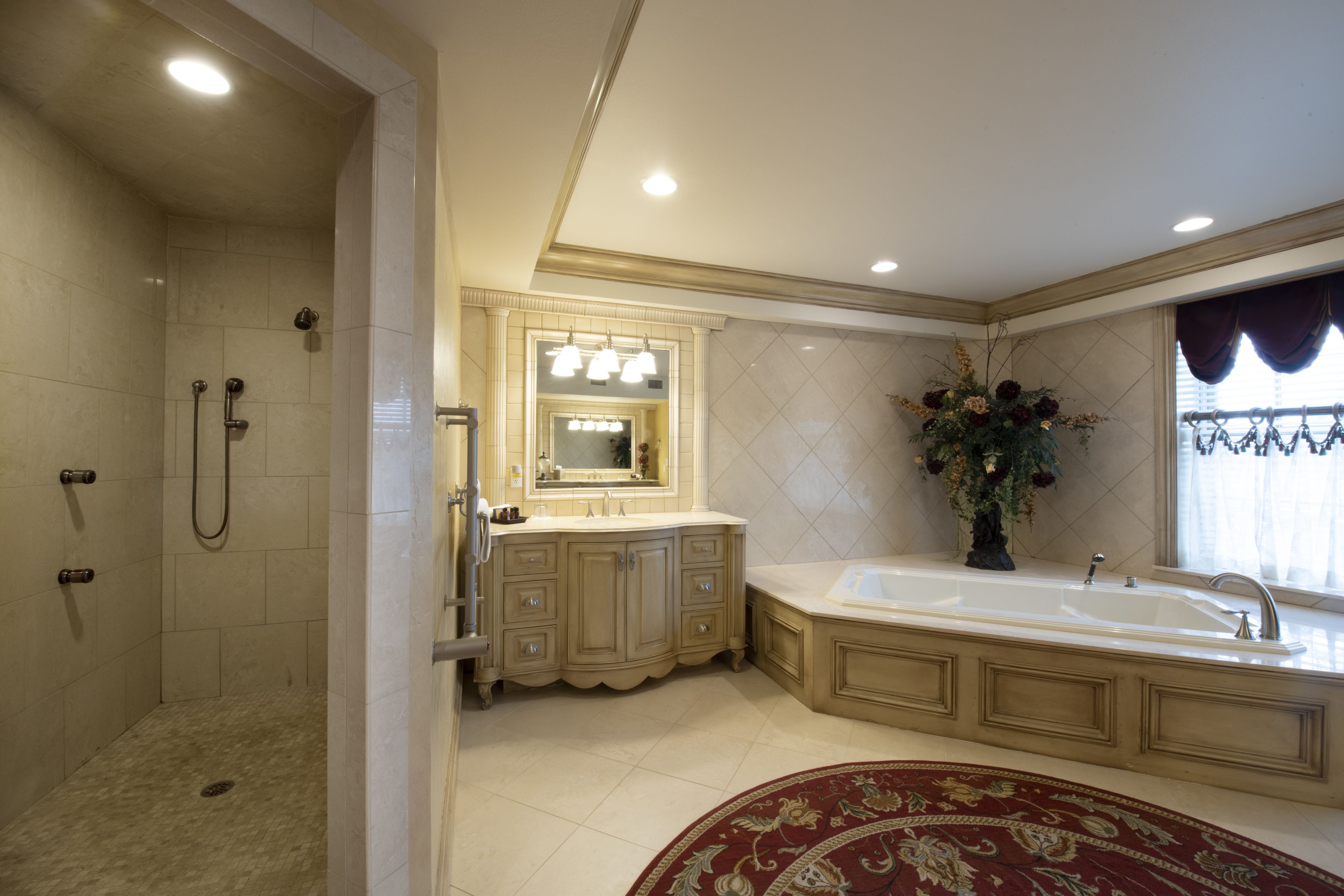 Une salle de bain spacieuse dotée d’une douche à l’italienne, d’une grande baignoire et d’un meuble-lavabo avec un miroir.