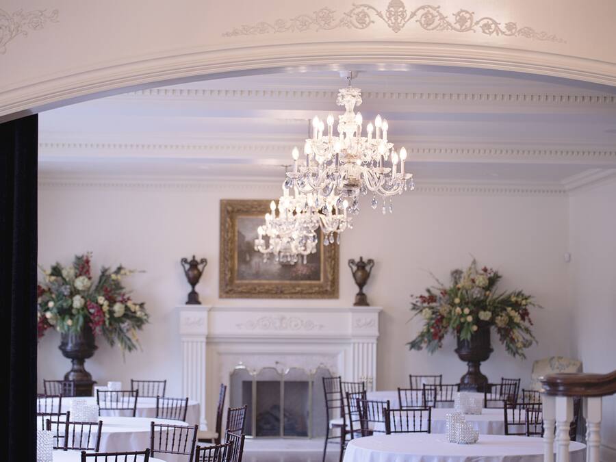 Un comedor formal con candelabro, paredes blancas y chimenea.