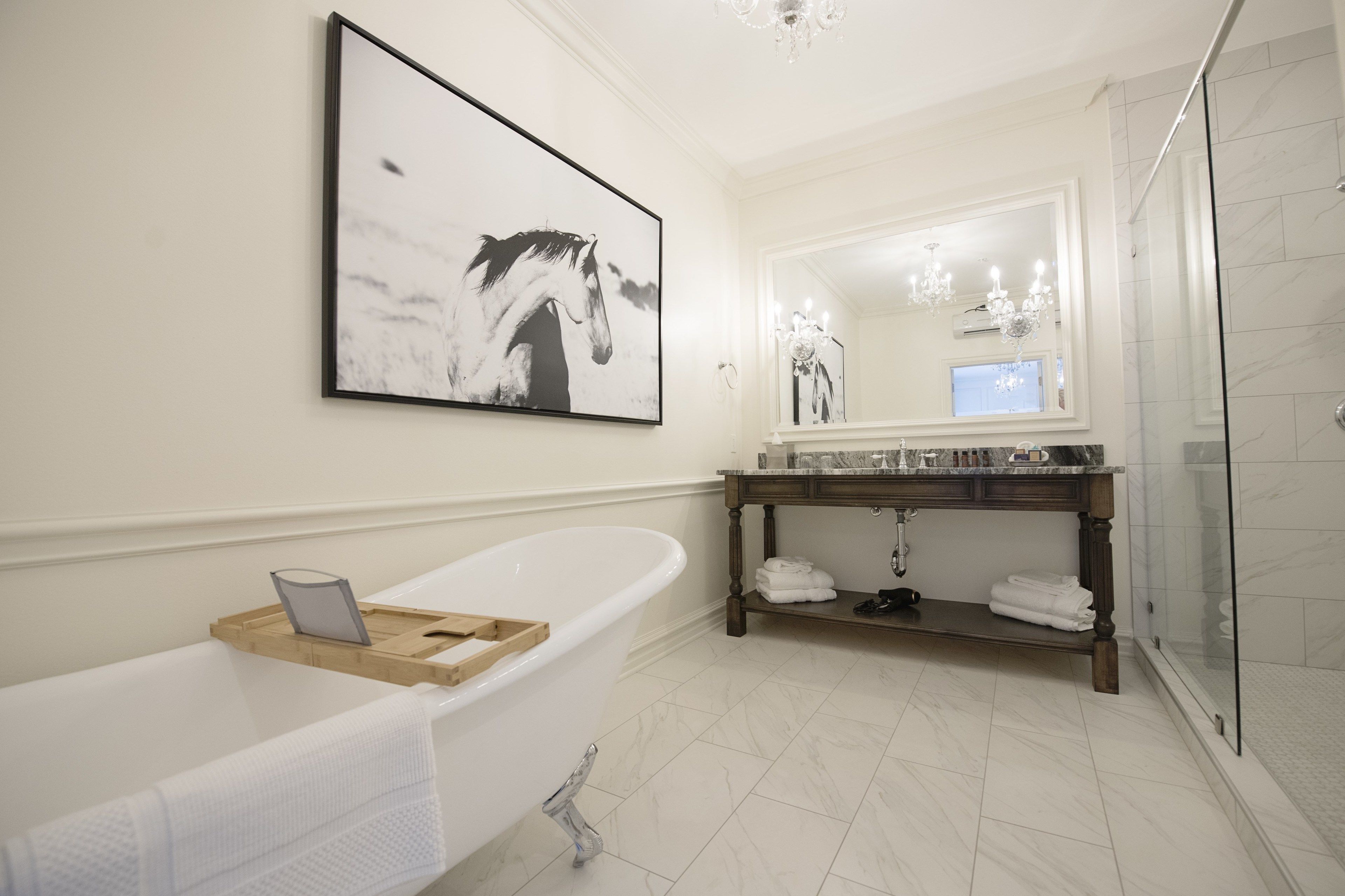 Une salle de bain moderne avec une baignoire sur pieds, un grand miroir et un meuble-lavabo doté d’un plan de travail en marbre.