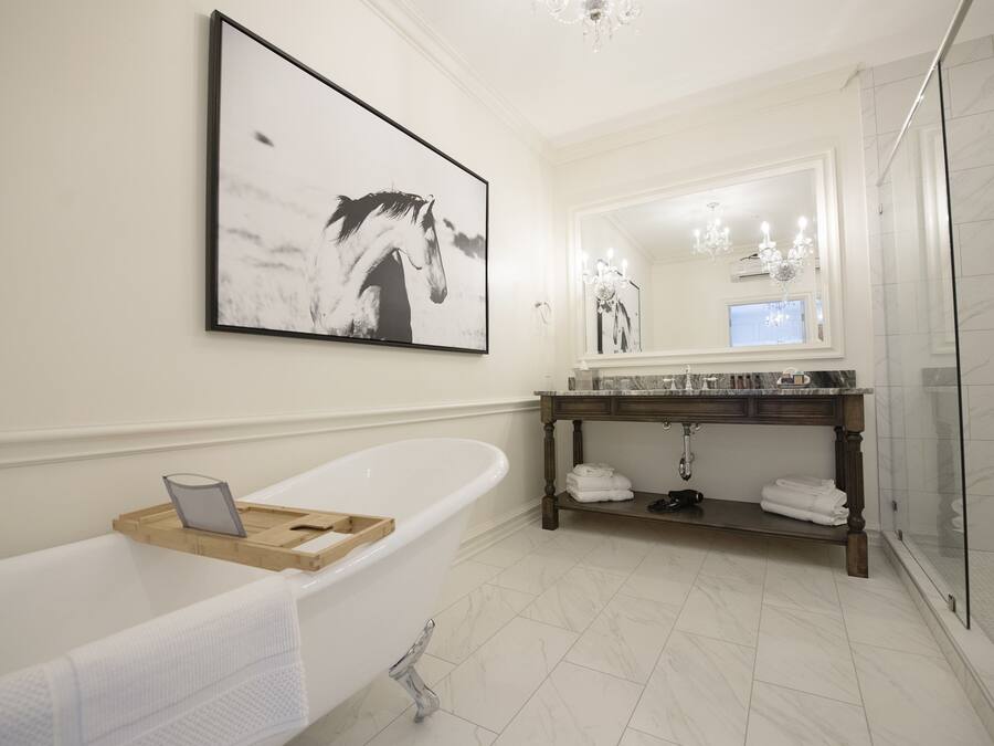 Une salle de bain moderne avec une baignoire sur pieds, un grand miroir et un meuble-lavabo doté d’un plan de travail en marbre.