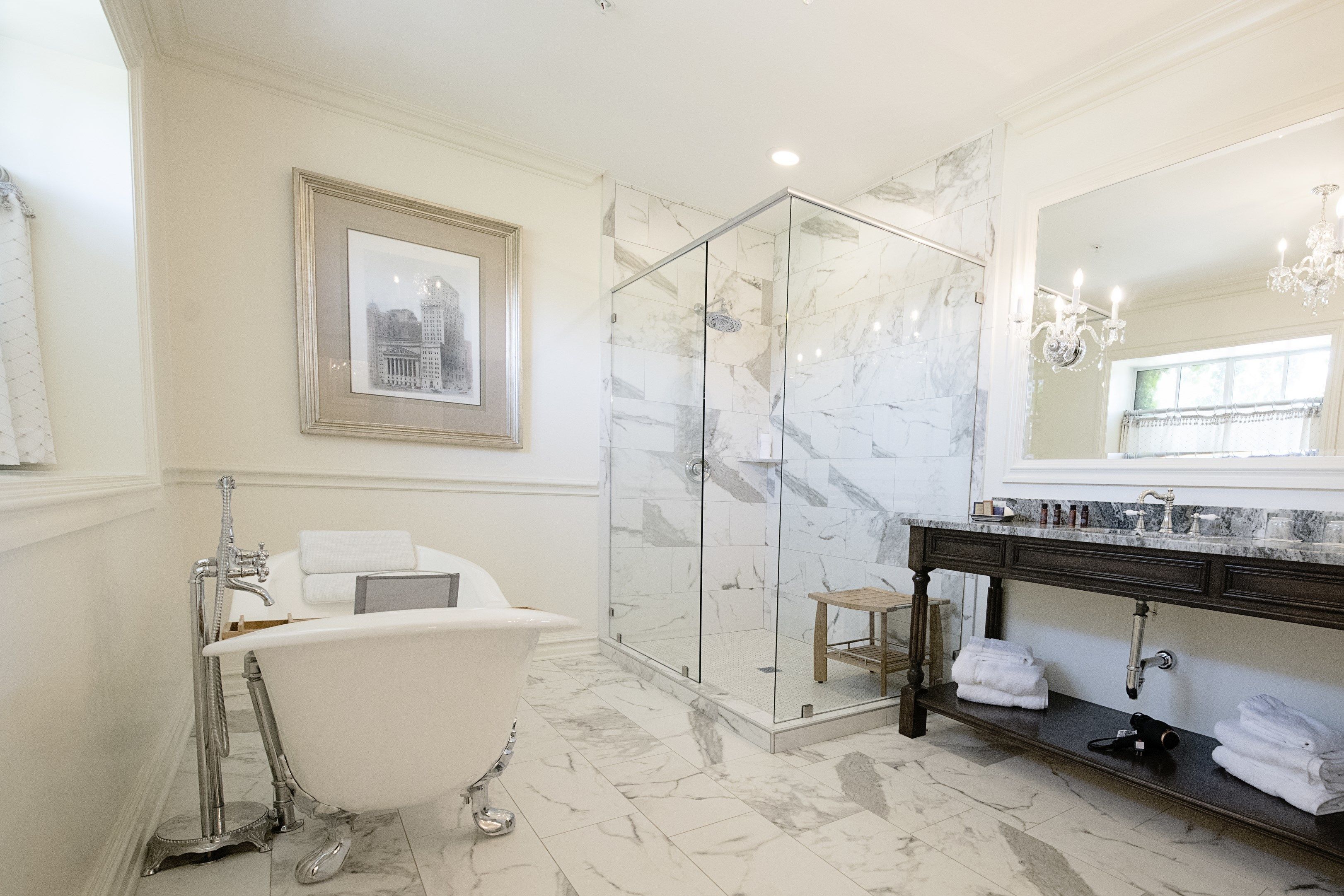 A bathroom with a bathtub, a glass-enclosed shower, a vanity with a mirror, and a framed picture on the wall.