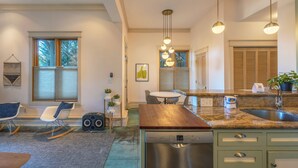 Een moderne keuken met een vaatwasser, een eethoek met een tafel en stoelen, en een zithoek met een schommelstoel.
