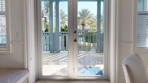 A room with a sliding glass door leading to a balcony with a view of palm trees and a pool. - Weekly Resort Activities & Family Fun - Marlin Bay (Marathon)