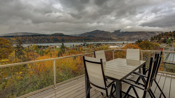 Eine Terrasse mit Tisch und Stühlen, die einen schönen Blick auf Berge und einen See bietet.