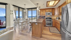 A spacious kitchen with a large island, wooden cabinets, stainless steel appliances, and a view to the outside. - Phoenix 8 1101 | Beachfront View | Spacious Corner Condo | My Beach Getaways (Orange Beach)