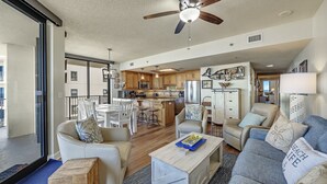 A spacious living area with a kitchen, dining area, and a balcony. - Phoenix 8 1101 | Beachfront View | Spacious Corner Condo | My Beach Getaways (Orange Beach)