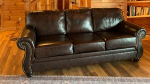 Ein Holzinnenraum mit einer Ledersofa, einer Treppe und einem Bücherregal.