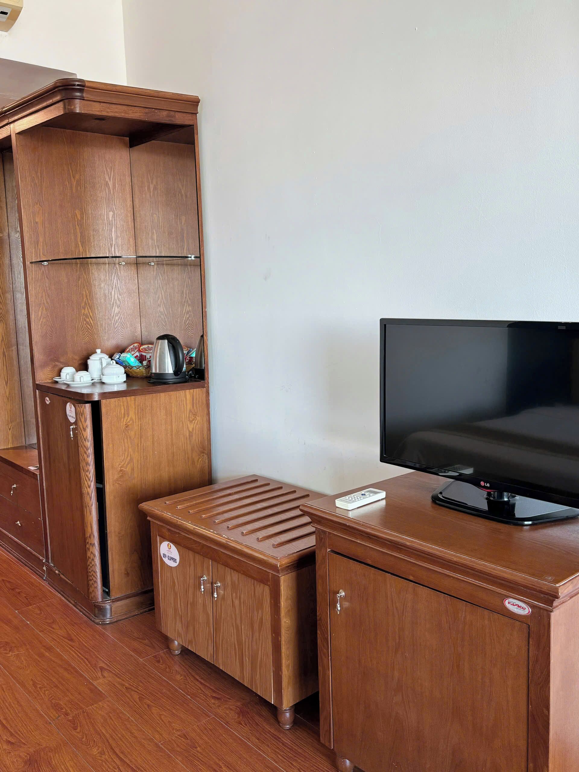 Een houten kast met een televisie erop, een kleine tafel en een plank met keukengerei.