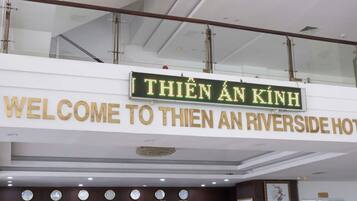 A hotel sign with "THIEN AN KINH" and "WELCOME TO THIEN AN RIVERSIDE HOTEL" in English and Vietnamese.