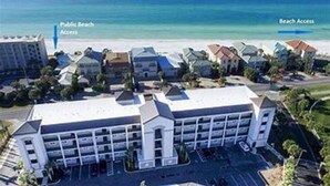 Et hotel med en stor parkeringsplads, et skilt der viser adgang til offentlig strand, og et skilt til strandadgang.