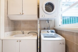 A compact laundry room with a washing machine, a sink, and cabinets. - Buckingham Pet friendly (Richmond)