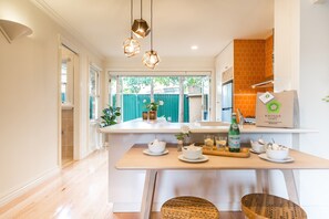 A modern kitchen with a central island, pendant lights, and a view of the outdoors. - Buckingham Pet friendly (Richmond)
