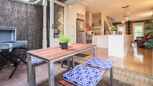 A modern kitchen with white cabinets, a central island, and a dining area with a wooden table and benches. - Buckingham Pet friendly (Richmond)