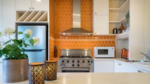 A modern kitchen with a stainless steel stove, oven, and microwave. There are decorative plants and candle holders on the counter. - Buckingham Pet friendly (Richmond)