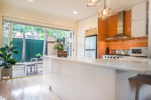 A modern kitchen with a large island, stainless steel appliances, and a view of the backyard. - Buckingham Pet friendly (Richmond)