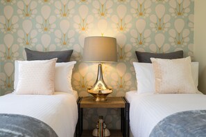A hotel room with two beds, a nightstand with a lamp, and a patterned wallpaper. - Buckingham Pet friendly (Richmond)