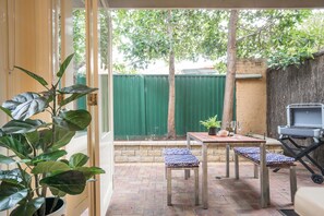 Un patio con mesa y sillas, una parrilla y plantas en macetas.