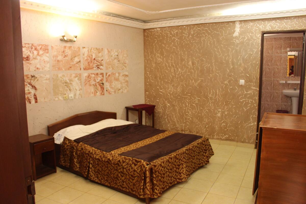 A bedroom with a bed, nightstand, and a mirror.