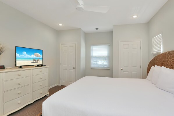 A bedroom with a large bed, a dresser, a television on the dresser, and two doors. - Close To The Beach, Community Pool, Plenty of Room ~ The Shore House (St. Joe Beach)