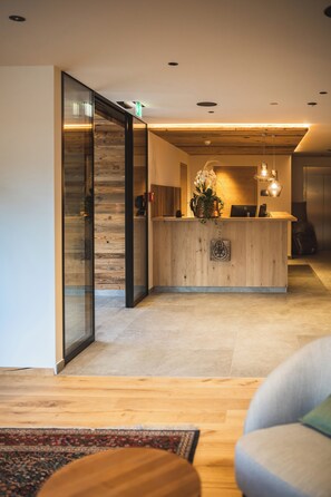 Un área de recepción moderna con un mostrador de madera, una computadora portátil y un florero con flores.
