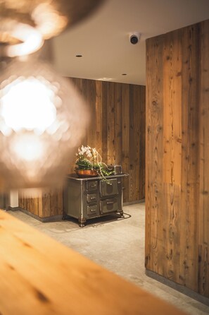 A room with wooden panel walls, a kitchenette with cabinets, and a potted plant on the counter. - Arthotel Gratschwirt (Dobbiaco)
