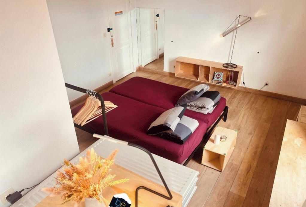 A room with a bed, a desk, a lamp, and a shelf with decorative items.