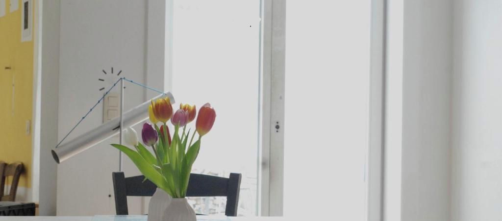 Ett rum med en vit dörr, en klocka på väggen och en vas med blommor på ett bord.