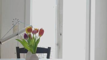 Ett rum med en vit dörr, en klocka på väggen och en vas med blommor på ett bord.