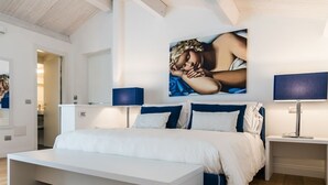 A bedroom with a large bed, bedside tables, a mirror, and a painting on the wall. - Cafe Bleu Relais (Sassari)