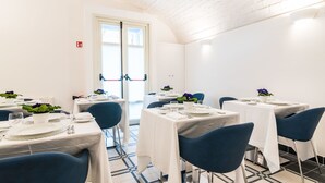 A dining area with tables set for four, each with white tablecloths, blue chairs, and blue flowers. - Cafe Bleu Relais (Sassari)