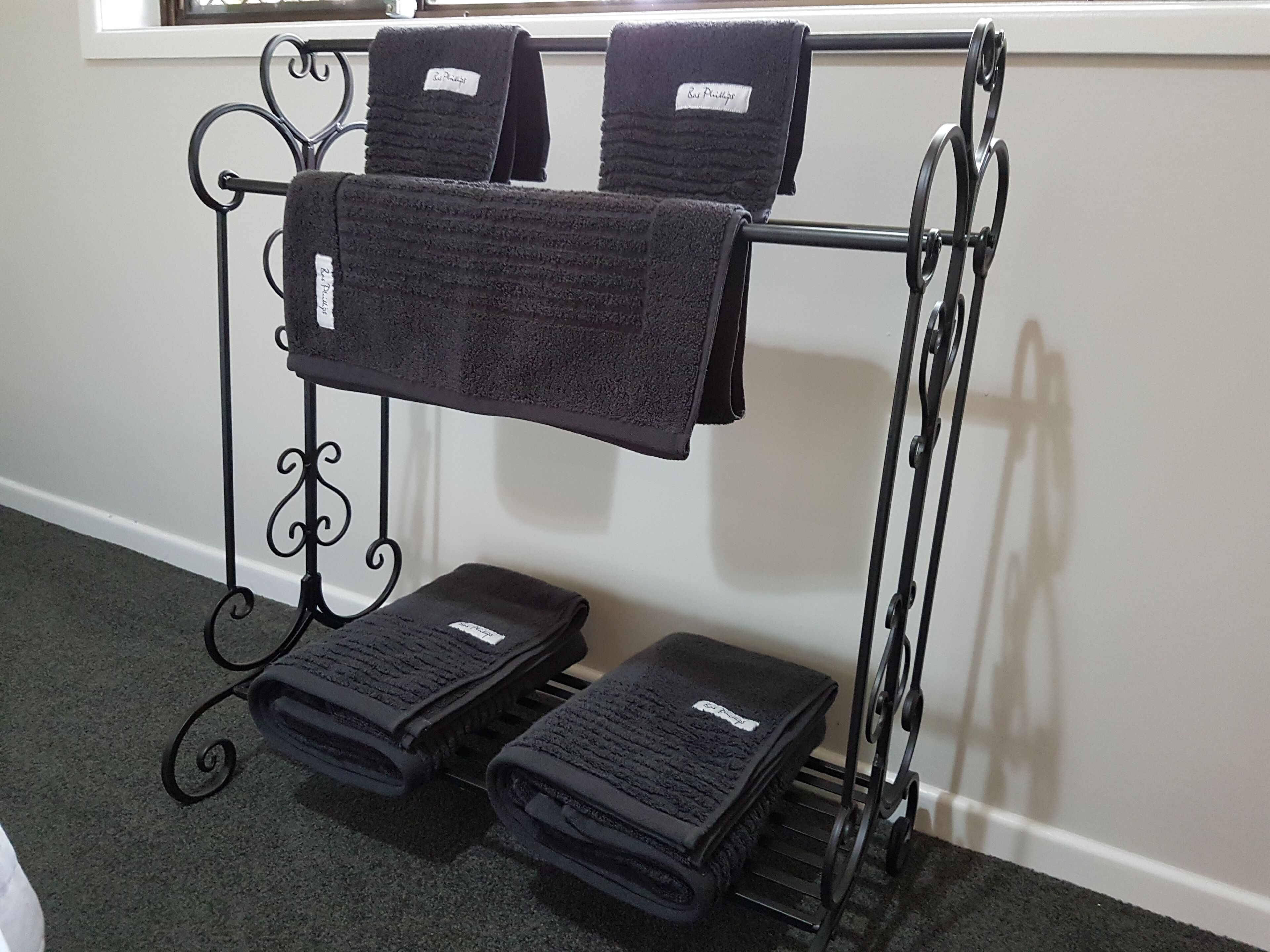 A metal towel rack with folded towels and a label.