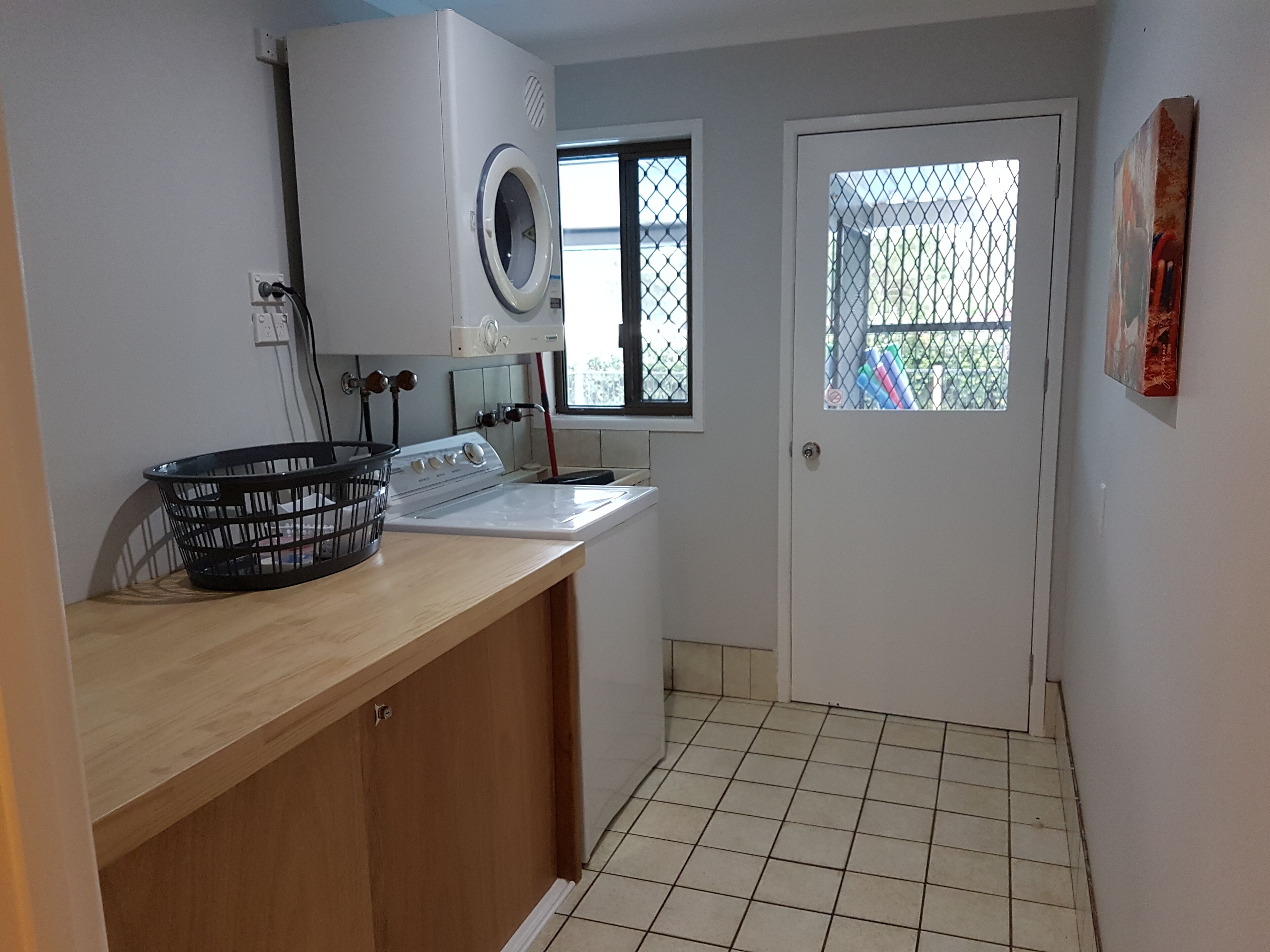A laundry room with a washing machine, dryer, and a window with a view.