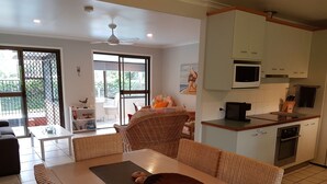 A modern living room with a dining area, kitchen, and sliding glass doors to a balcony. - Beerwah House, 3Bedroom , swimming pool, near Australia Zoo, Sunshine Coast (Beerwah)