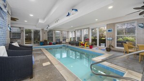 A pool area with wicker furniture, a glass-enclosed pool, and decorative fish on the ceiling. - 10Bd/10Ba Large Beach Home, Indoor Pool In Virginia Beach (Virginia beach)