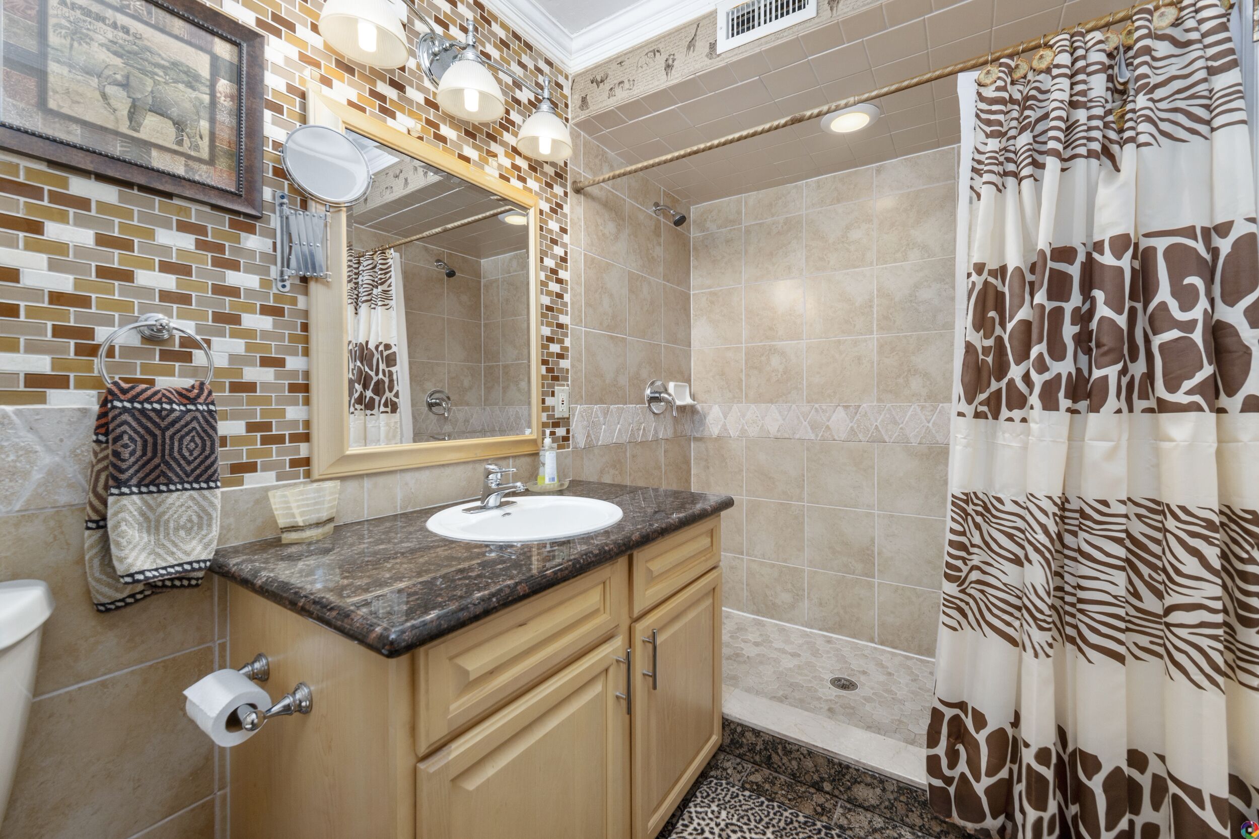 Un baño con ducha revestida de azulejos, lavamanos con espejo y toallero.