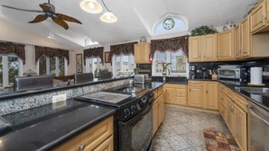 A kitchen with granite countertops, a black stove, wooden cabinets, and a ceiling fan. - 10Bd/10Ba Large Beach Home, Indoor Pool In Virginia Beach (Virginia beach)
