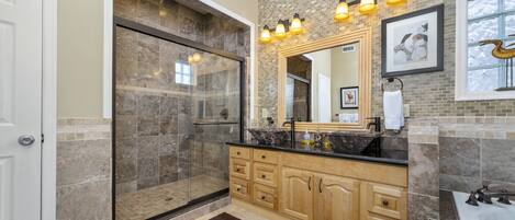 Un baño moderno con ducha de vidrio, un espejo grande y una bañera.