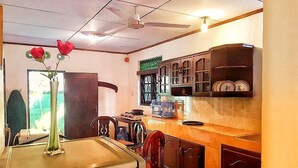 Una cucina con zona pranzo, ventilatore a soffitto e finestra con persiane.