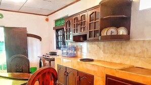 Una cucina con mobili in legno, zoccolo a mosaico e zona pranzo con una sedia e un tavolo.