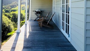 A covered porch with a view of a green landscape, a grill, and a table with chairs. - Broughton Cottage - Pudding Hill Farm, Berry (Foxground)